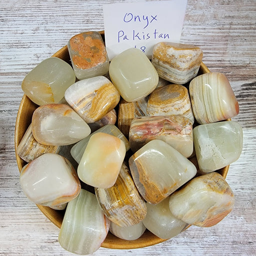 A beautiful piece of Banded Onyx tumbled stone showcasing its unique striped patterns in light tan to brown, symbolizing strength and perseverance.